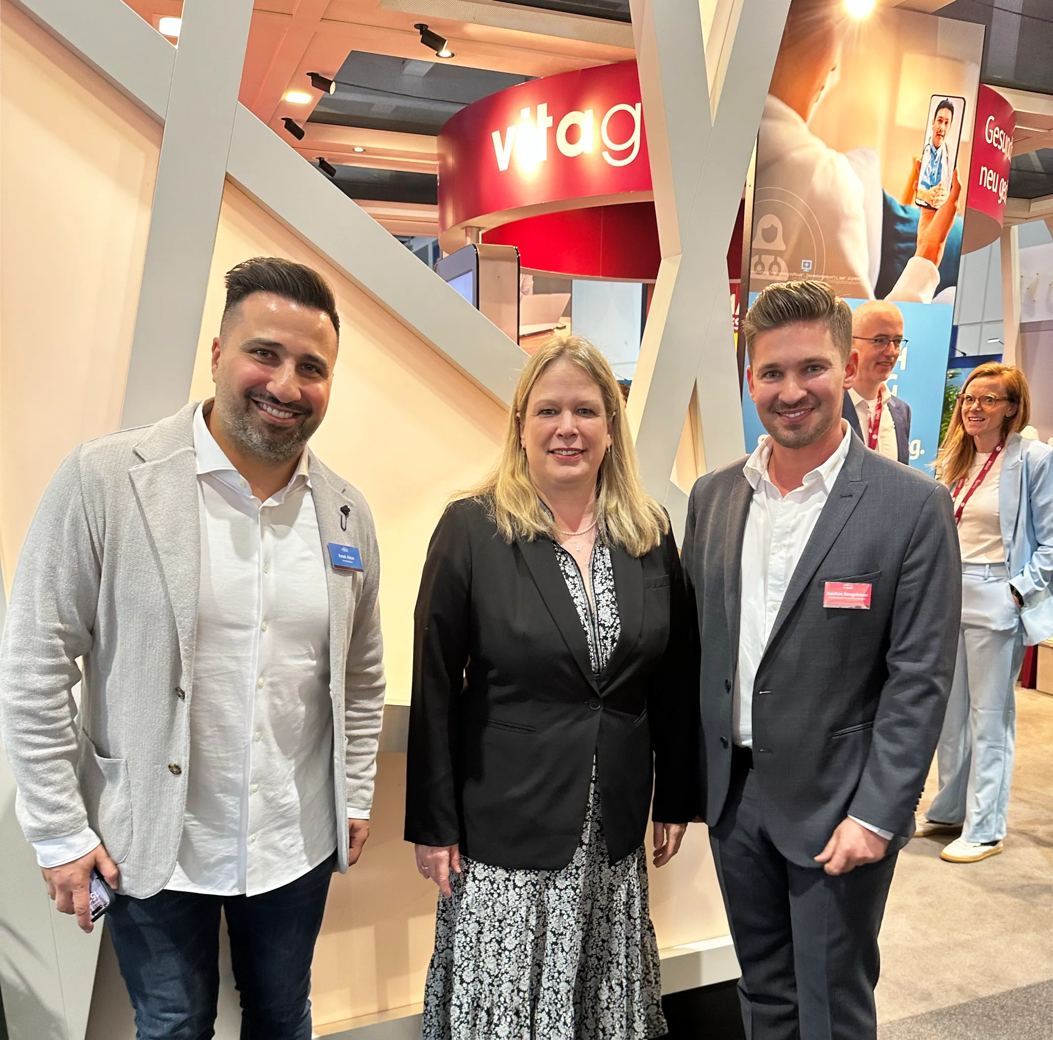 2 Männer und eine Frau schauen lächelnd in die Kamera auf der Messe für digital health