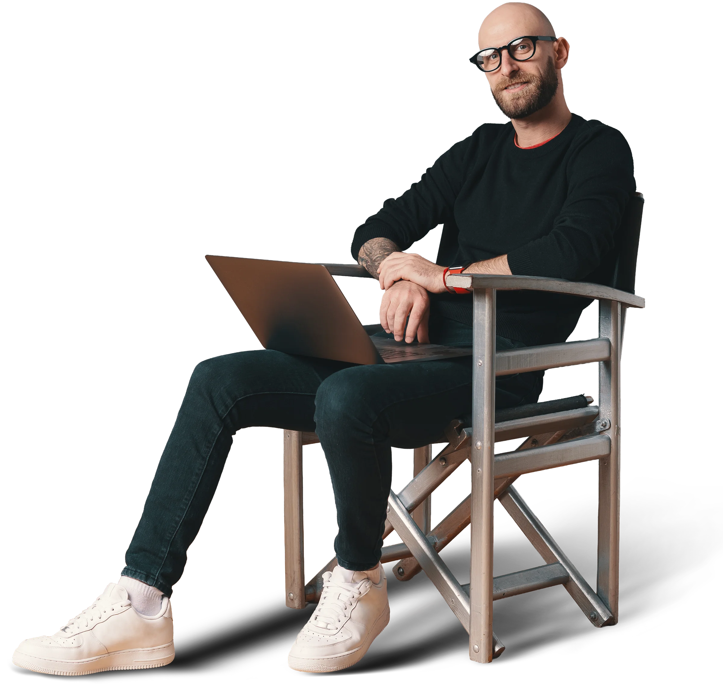 Man with glasses sitting relaxed on a wooden chair with a laptop on his lap, cut out on transparent background
